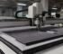 A CNC oscillating knife cutting machine processing multi-layer textile fabric in a Karachi production facility